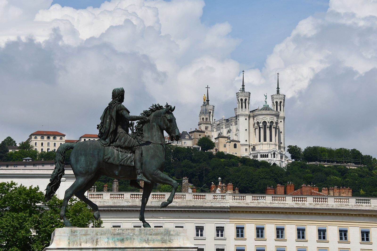 Meilleur team building à faire à Lyon : la statue équestre de la place Bellecour, avec la basilique de Fourvière en arrière-plan