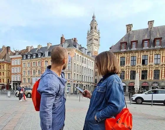 Deux joueurs en mission sur la Grand Place de Lille, smartphone en main